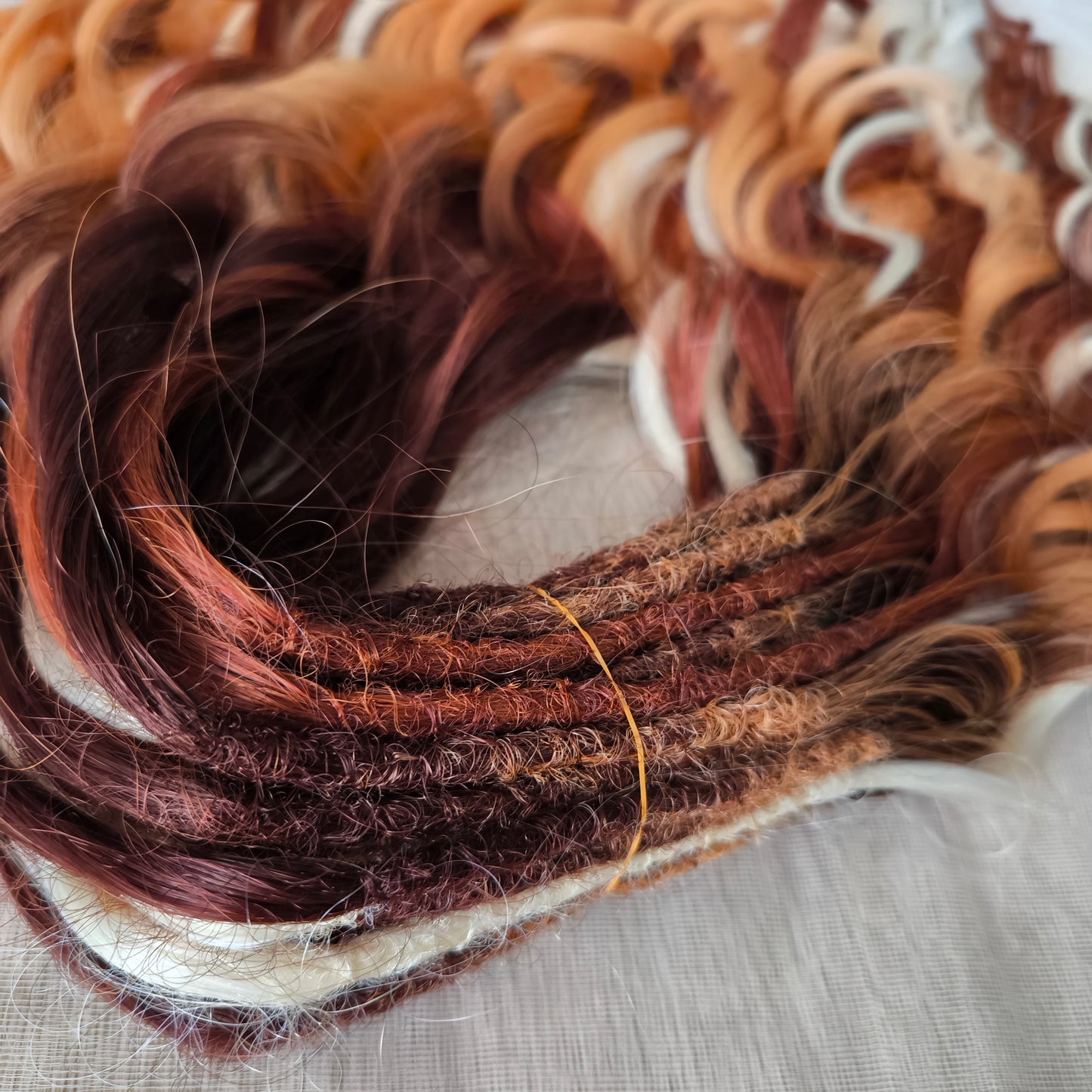 This set combines a rich three-tone ombré gradient — deep chestnut, warm copper, and pale blonde — with additional solid strands in copper and creamy platinum, creating a stunning play of light and color.
Inspired by autumn leaves, glowing embers, and the graceful energy of a wild fox, Amber Fox is made to stand out with both softness and strength.
Soft, lightweight, and reusable synthetic brushable double ended wavy dreadlocks (available as regular dreaded, braided middle, or push-up).