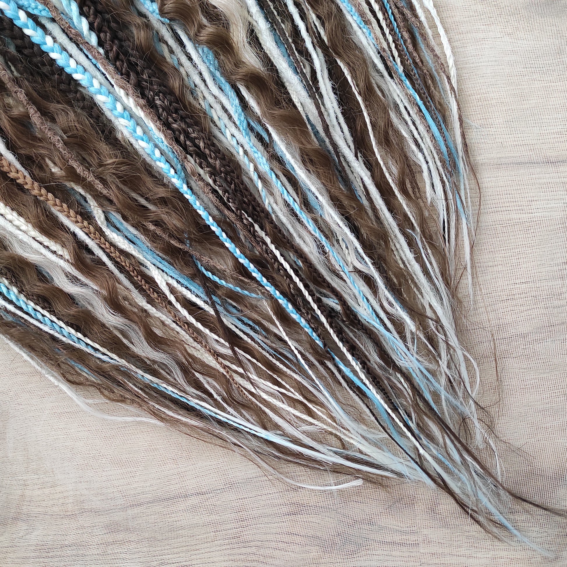 A calm mix of cocoa brown, creamy blonde, and bright blue accents — lightweight, brushable, and reusable synthetic DE curls and braids.