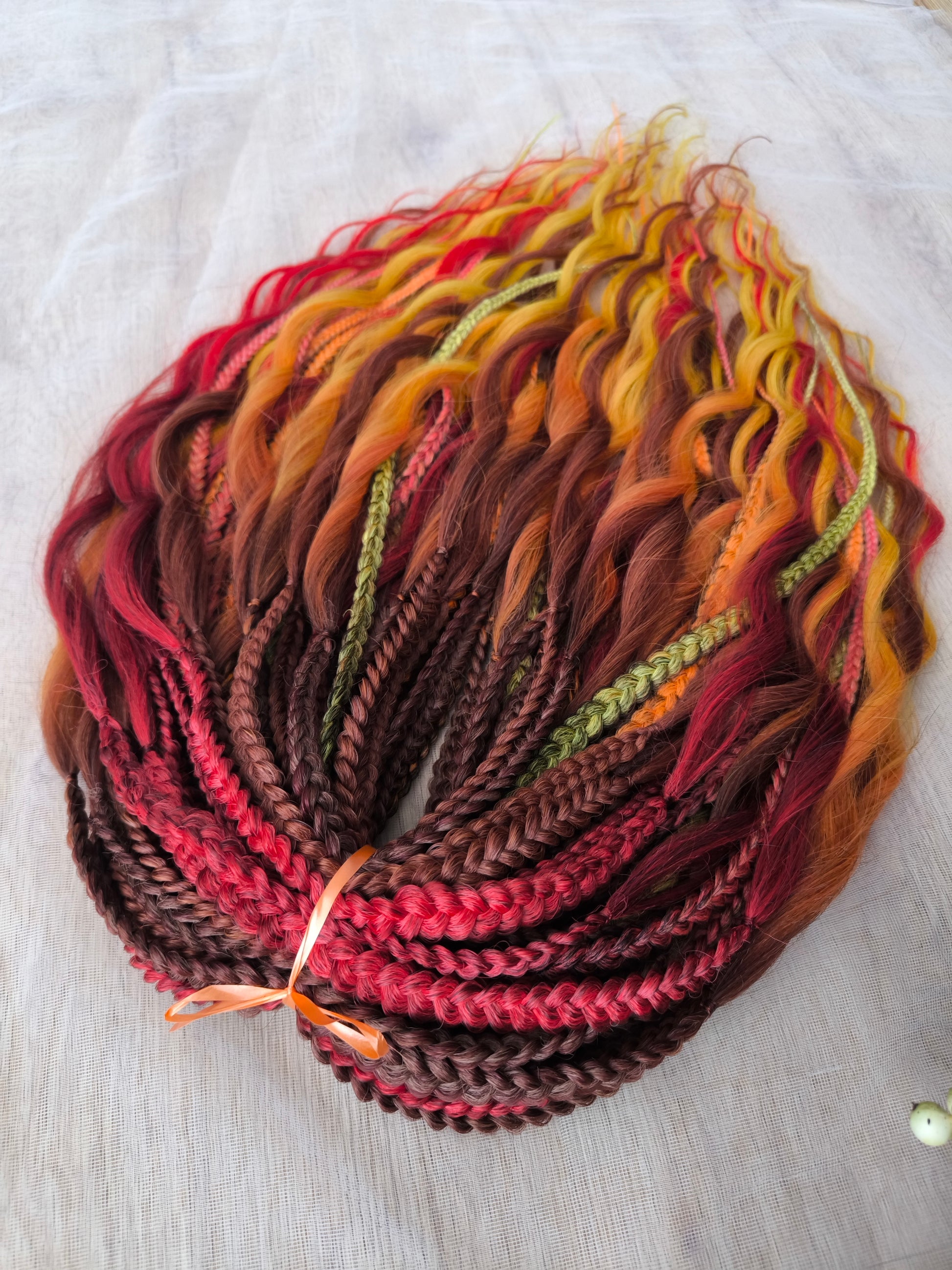 Mountain Sunrise: soft, lightweight, and reusable 55 double-ended synthetic braids with loose wavy brushable ends in red, bronze, yellow, and orange colors.
