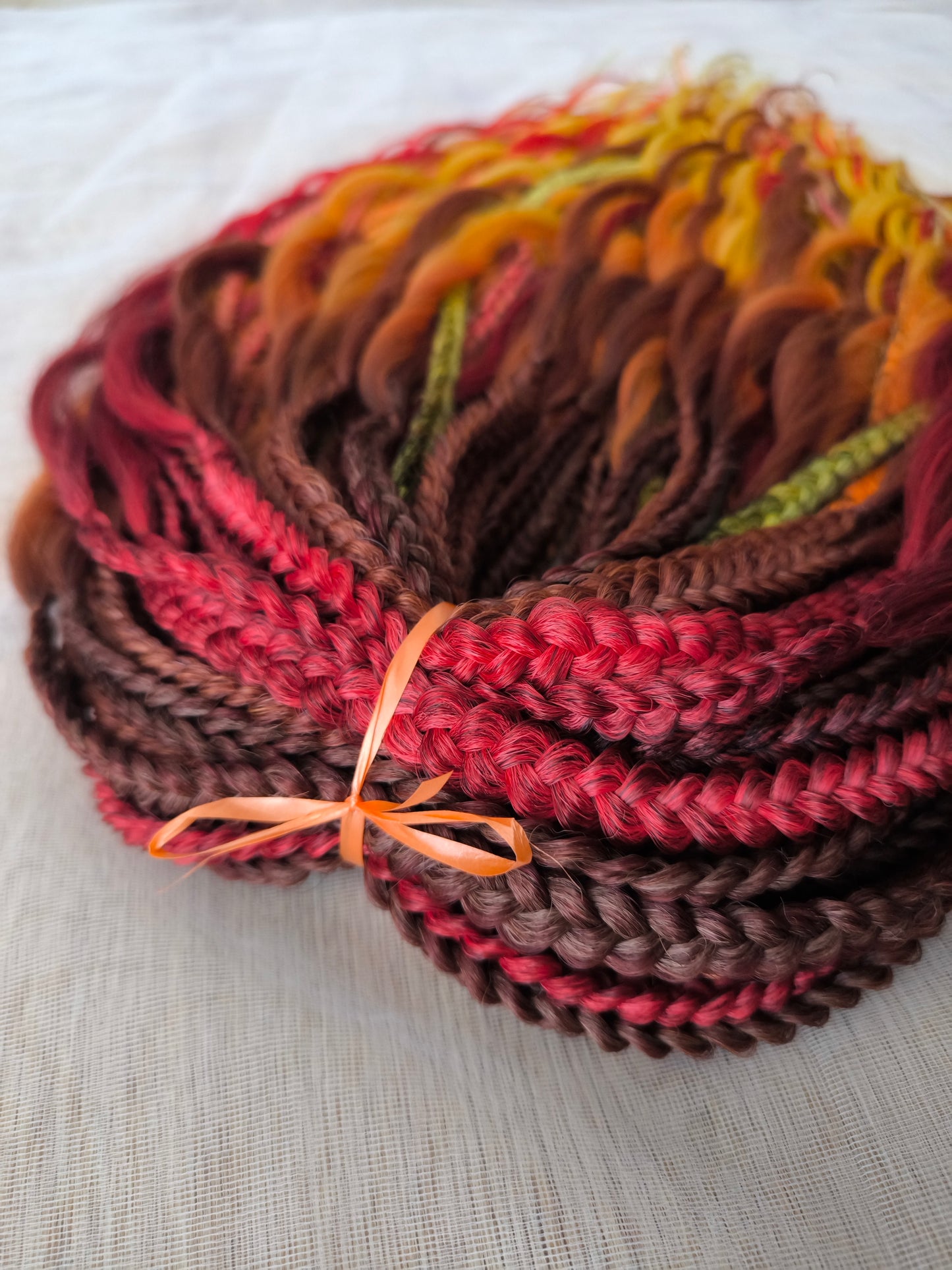 Mountain Sunrise: soft, lightweight, and reusable 55 double-ended synthetic braids with loose wavy brushable ends in red, bronze, yellow, and orange colors.