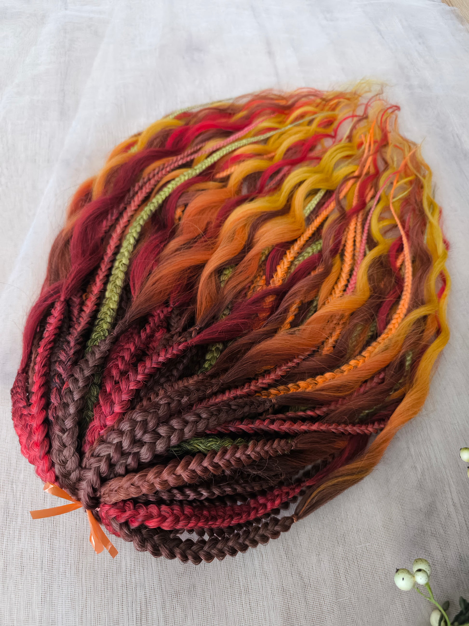 Mountain Sunrise: soft, lightweight, and reusable 55 double-ended synthetic braids with loose wavy brushable ends in red, bronze, yellow, and orange colors.