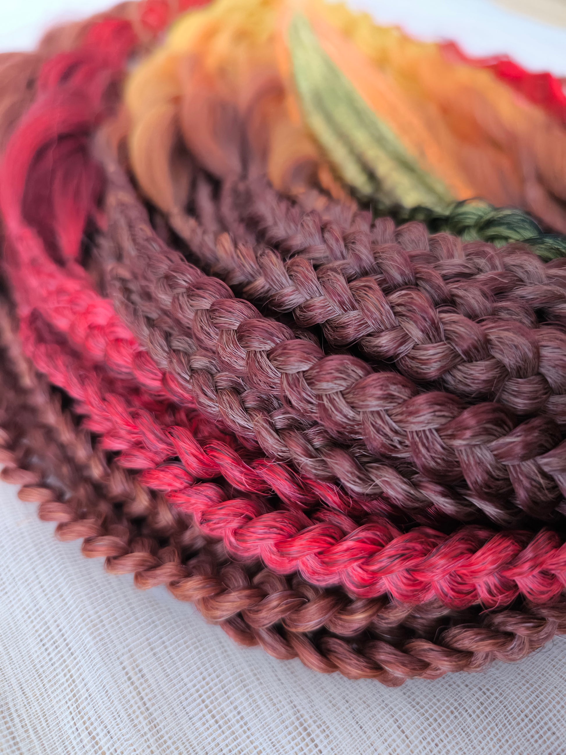 Mountain Sunrise: soft, lightweight, and reusable 55 double-ended synthetic braids with loose wavy brushable ends in red, bronze, yellow, and orange colors.