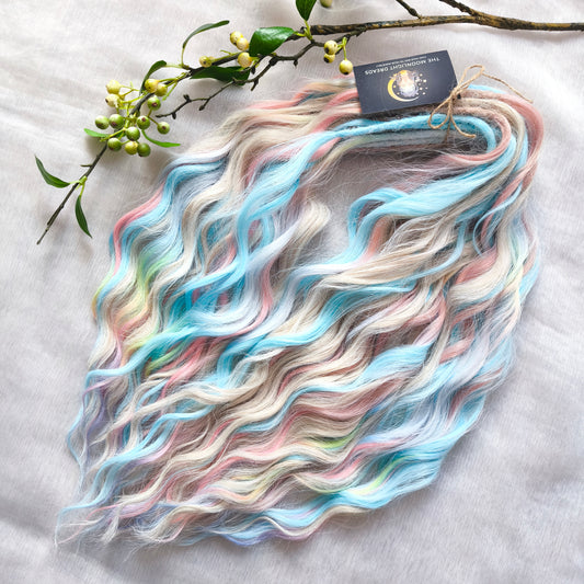 Ready to Ship: Cotton Candy - soft, lightweight, and reusable 50 double ended synthetic brushable dreaded curls. A blend of platinum blonde, sky blue, pink, and rainbow colors creates a light, airy look full of soft color transitions.