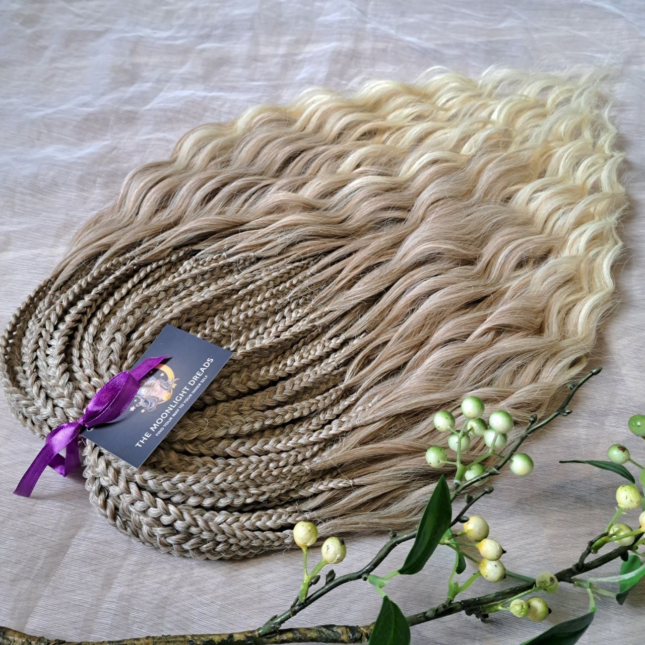 Ready to ship: soft, lightweight, and reusable 50 double ended synthetic brushable curls with braided middle. Soft natural gradient in warm neutral tones.

Roots in muted dark blonde with a subtle ash-beige (taupe) undertone, gradually blending into a warm beige-wheat blonde, and finishing in a light creamy, almost platinum vanilla blonde at the ends.