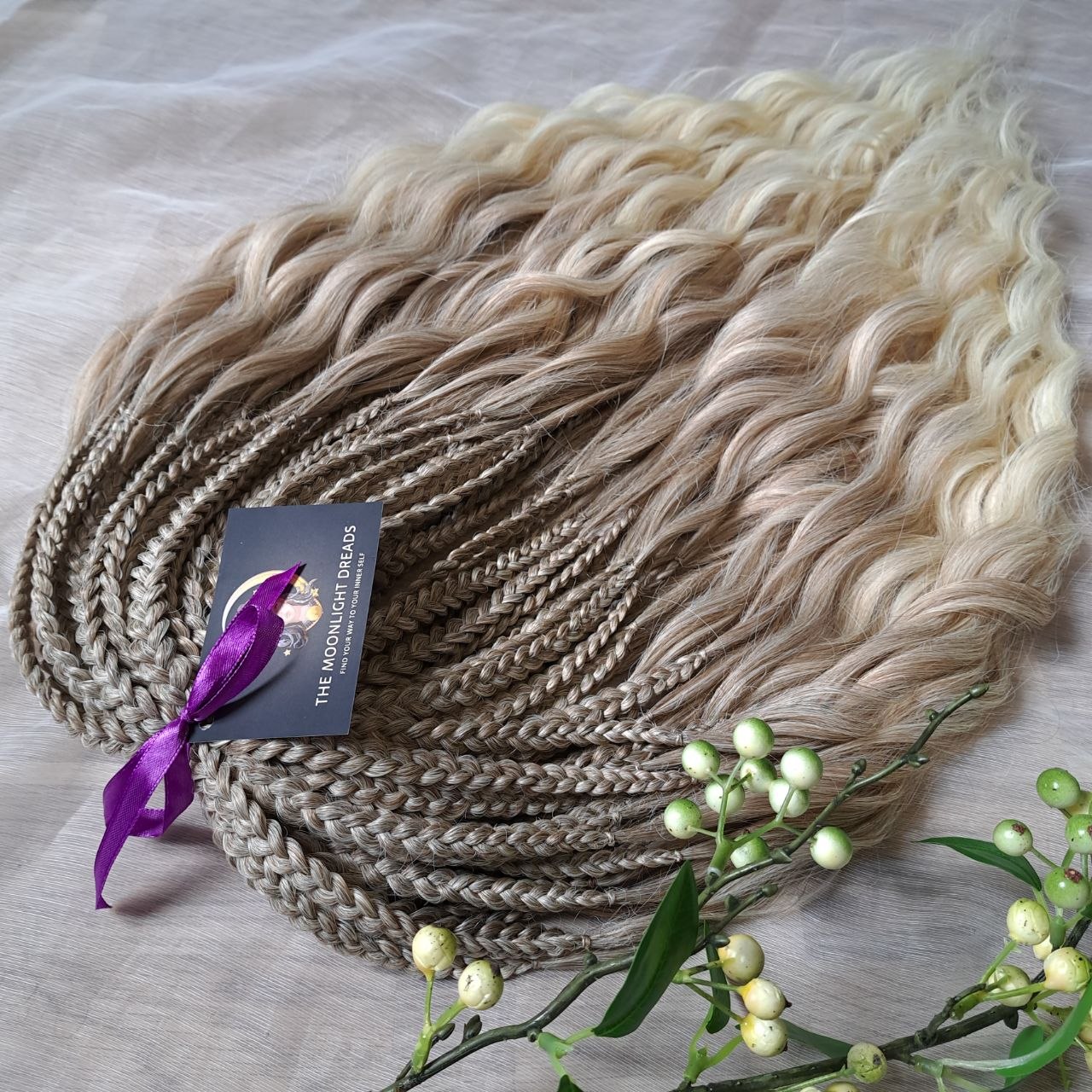 Ready to ship: soft, lightweight, and reusable 50 double ended synthetic brushable curls with braided middle. Soft natural gradient in warm neutral tones.

Roots in muted dark blonde with a subtle ash-beige (taupe) undertone, gradually blending into a warm beige-wheat blonde, and finishing in a light creamy, almost platinum vanilla blonde at the ends.