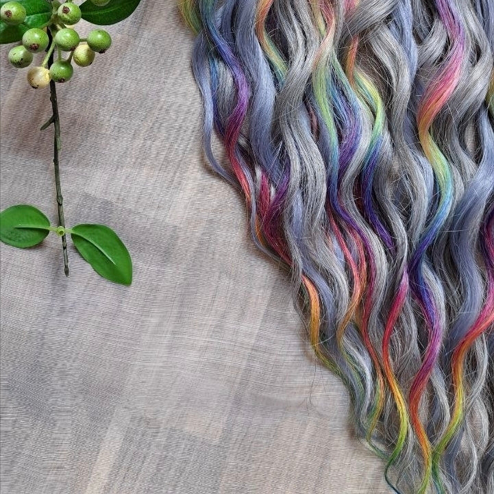 Silver Rainbow - soft, lightweight, and reusable synthetic brushable double ended wavy dreadlocks (regular dreaded, braided middle, or push-up).

A silver-grey base with vibrant rainbow accents. Bright pops of color stand out against the cool smoky background, creating a playful yet balanced look.
