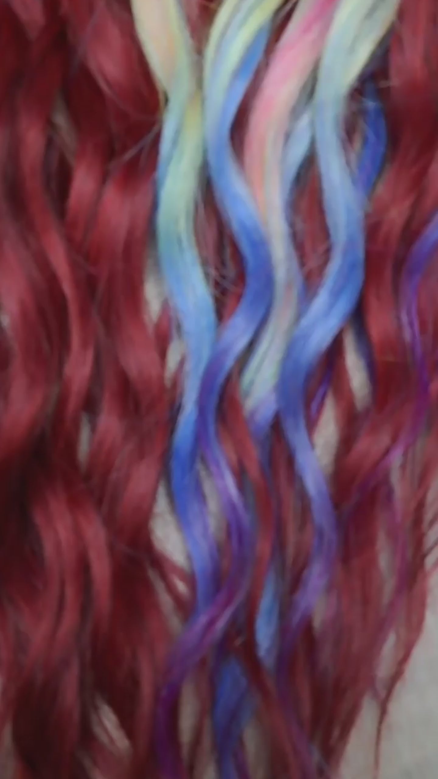 Deep berry red base with pastel highlights in blue, lilac, pink, and soft yellow - bold contrast with a smooth flow of color. Soft, lightweight, and reusable synthetic brushable double ended wavy dreadlocks. Bring the burst 💥